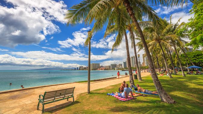 Waikiki ,Oahu, Hawaii, United States - August 27, 2016: people take the sun lying on the lawn fronting the popular Queen's Beach section of Waikiki Beach.