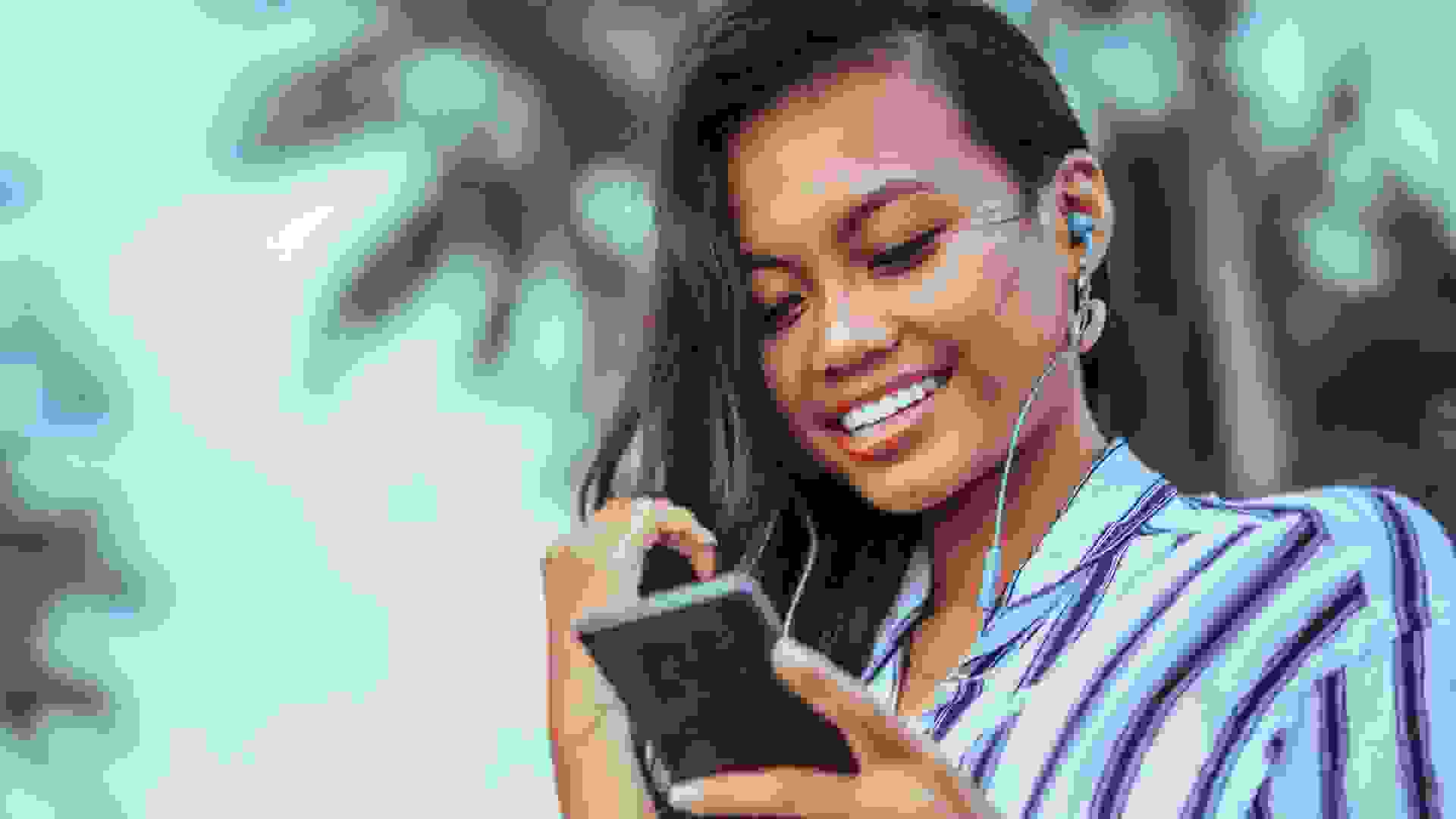 Young woman with phone and earphones at the beach.