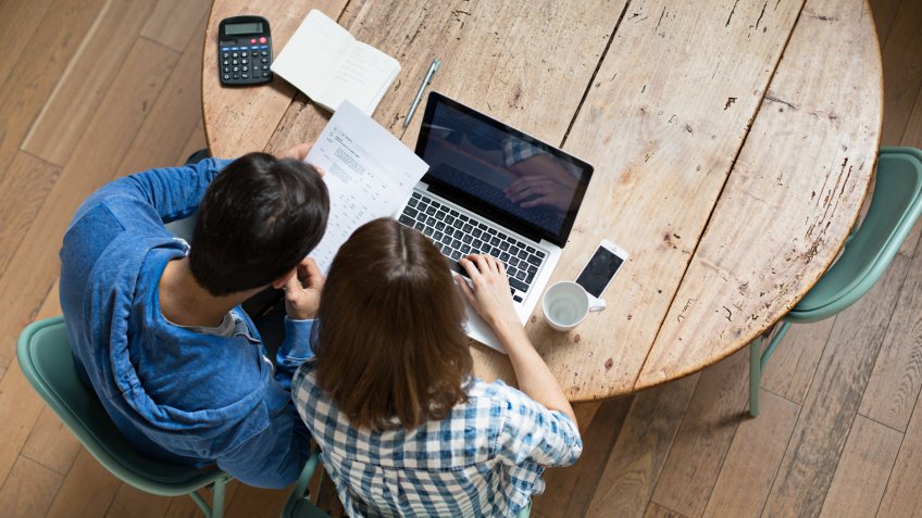 Elevated view from a young couple checking their home finances at home.