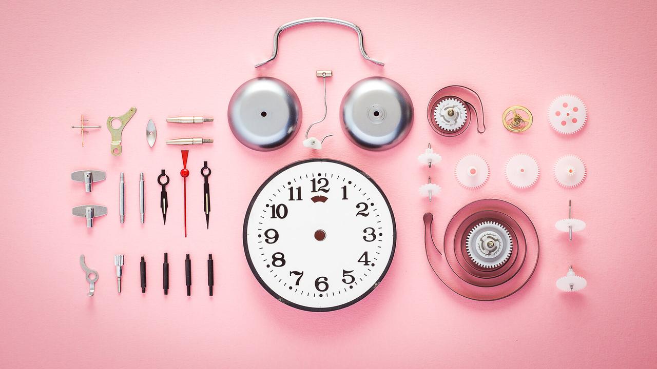a disected alarm clock on pink background