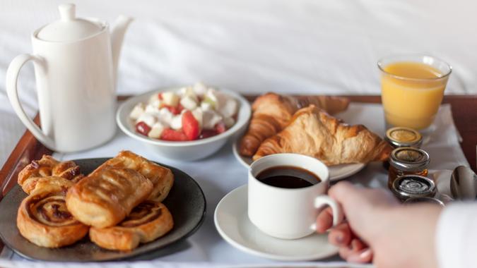 Bed breakfast with coffee cup, croissants and orange juice on white sheets.