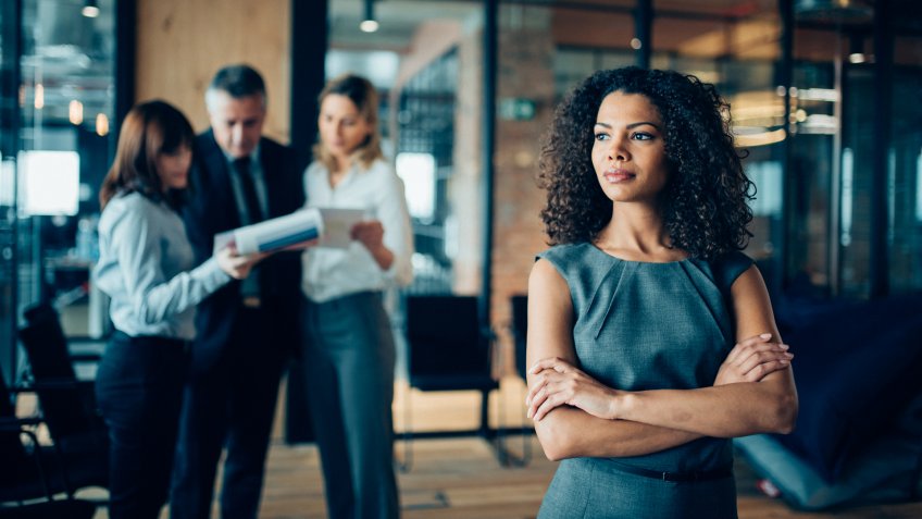 Beautiful african-american ethnicity woman sitting confidently in office looking away.
