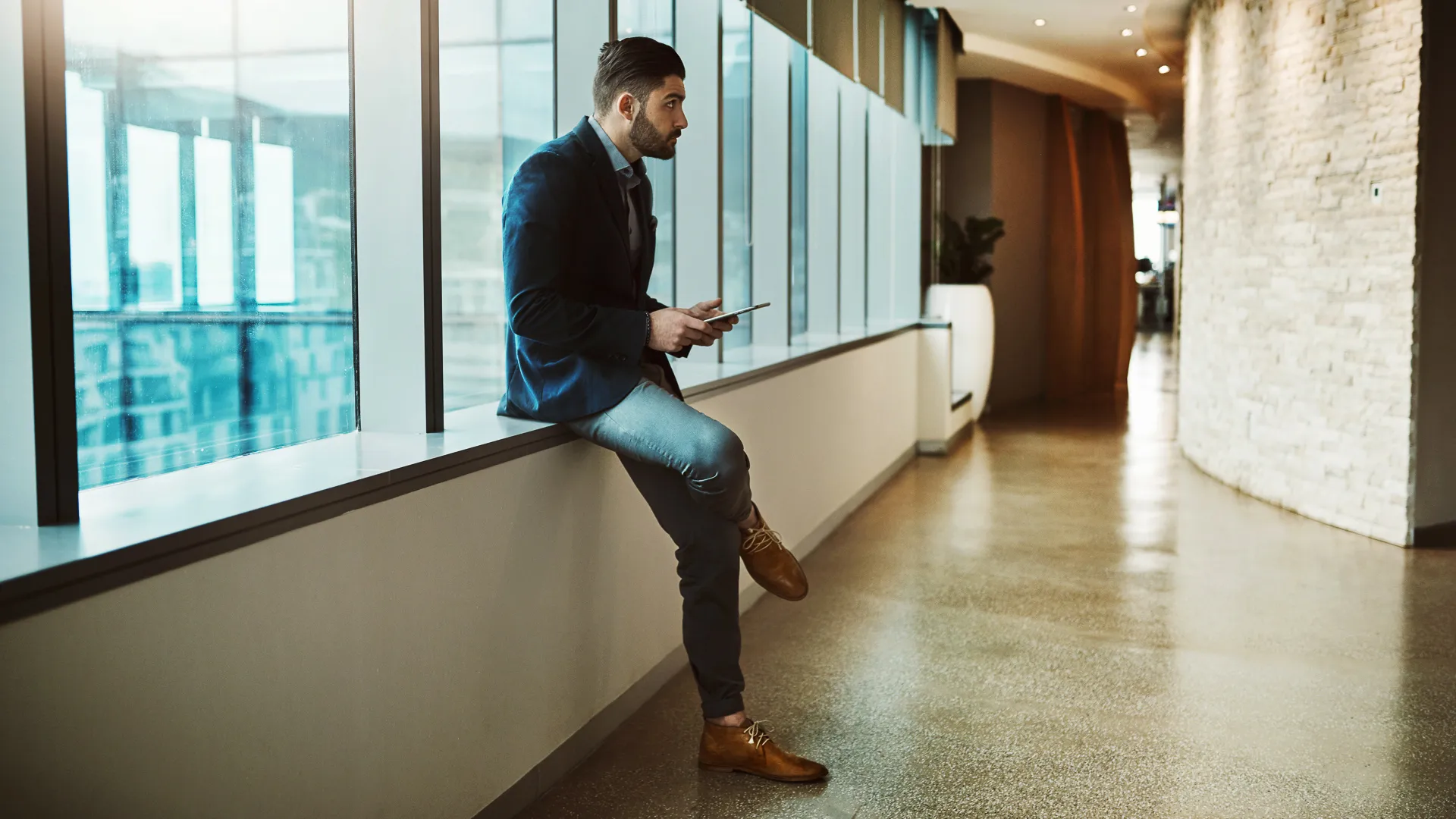 Shot of a young businessman looking thoughtful while using a digital tablet in a modern office.