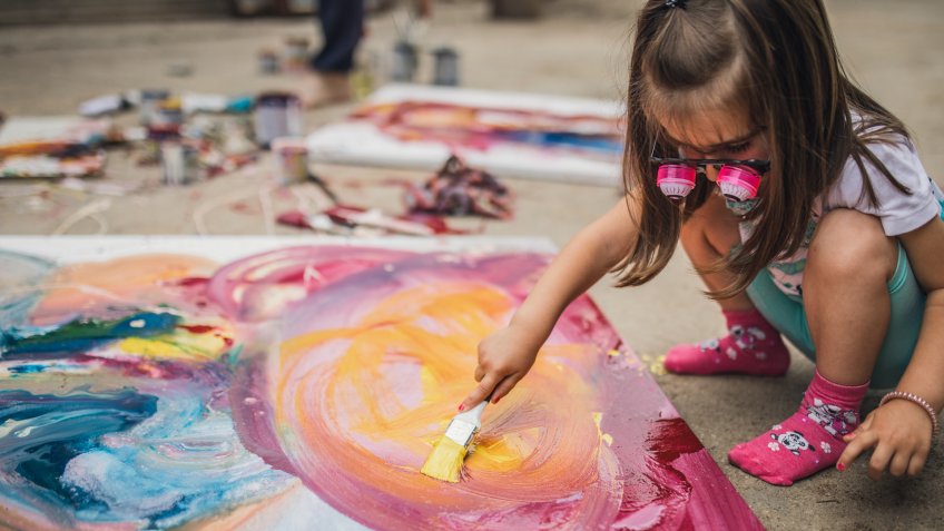 Little girl painting outdoors.