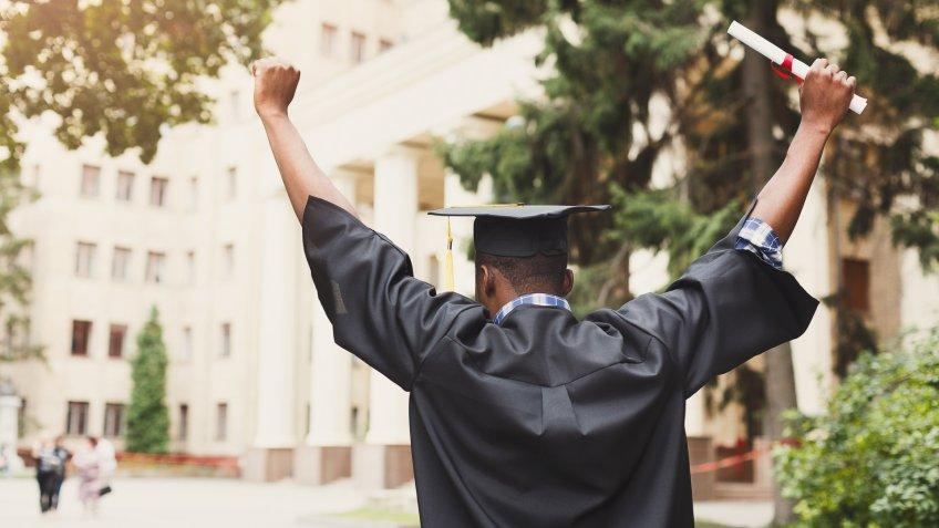 Young woman on her graduation day in university holding diploma.