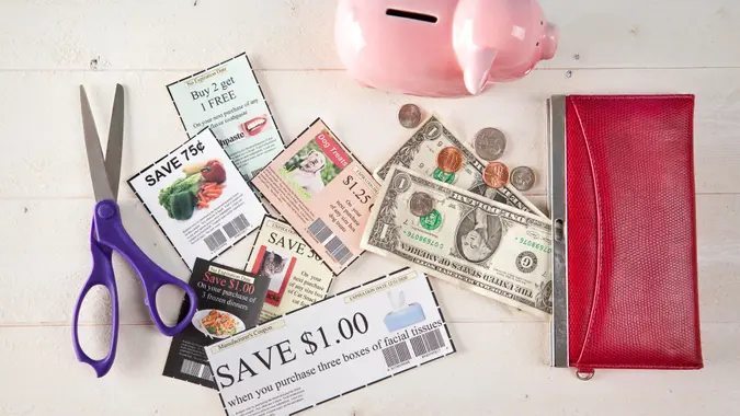 Coupons, scissors, money, wallet and a piggy bank.