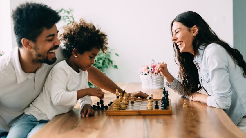 Happy family playing chess together at their home.