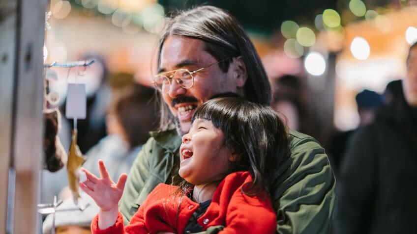 A father is shopping at Christmas market with his two daughters.