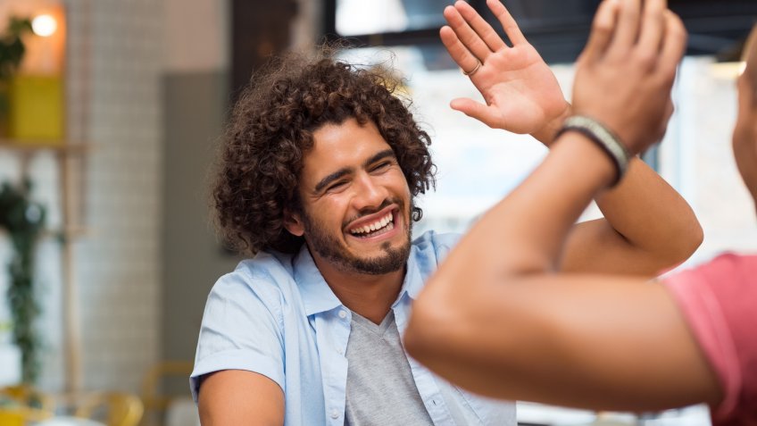friends giving high five at cafe while having lunch.