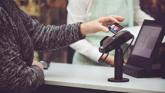 Close-up of senior woman paying contactless with credit card.
