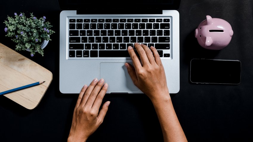 Woman hands typing on keyboard on blue desk.