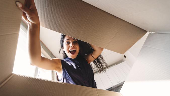 Smiling woman opening a carton box Pretty young happy woman opening a carton box.