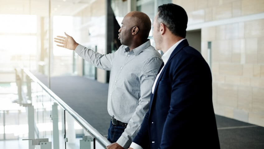 Cropped shot of a handsome mature businessman showing his male colleague something in their corporate office.