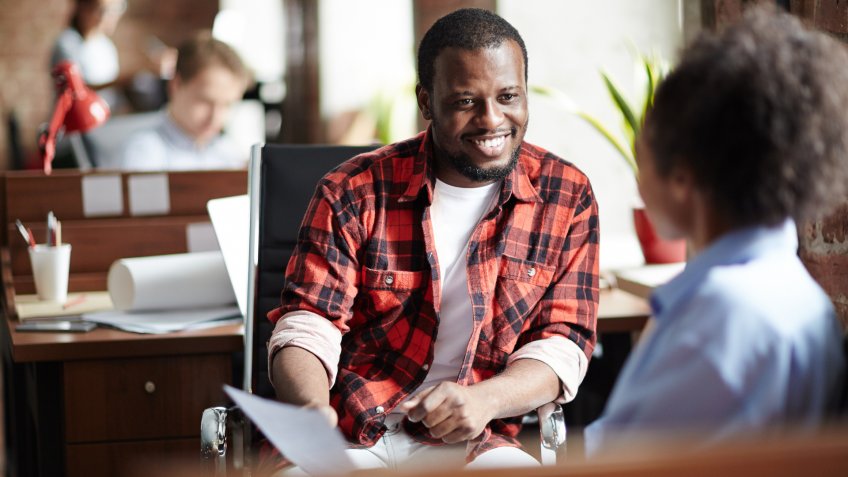 Smiling African businessman in casual clothes conducting the interview with woman at office.