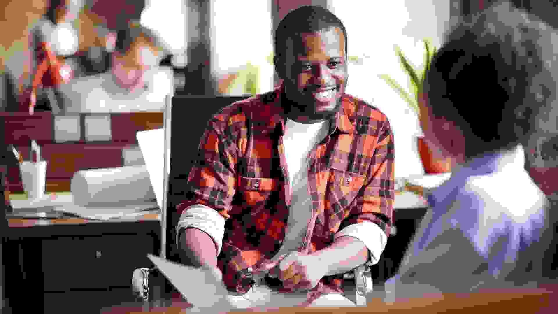 Smiling African businessman in casual clothes conducting the interview with woman at office.