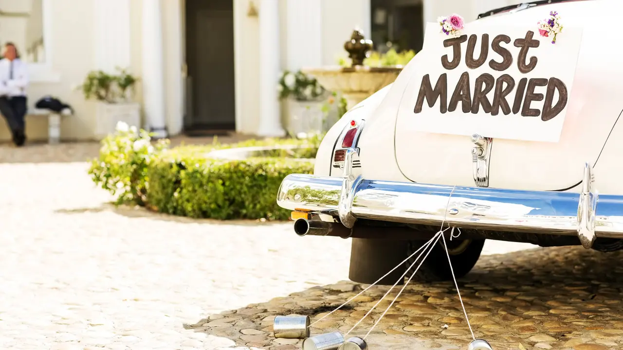 Just married sign and cans attached to convertible car.