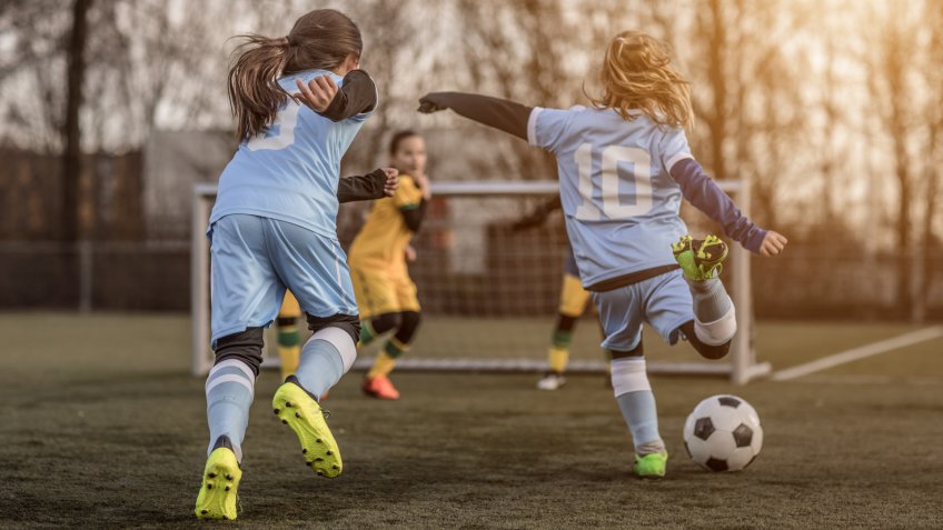 Two Female Girl Soccer Teams playing a football training match in the Spring outdoors.