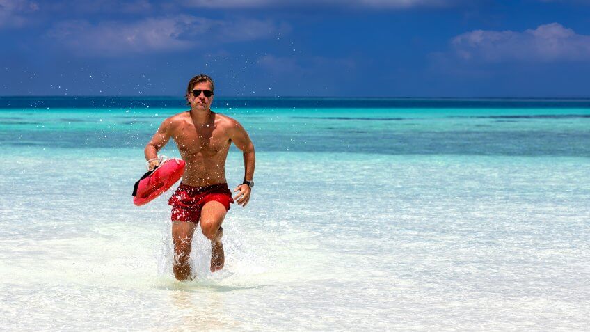 Male lifeguard running in turquoise waters in the Maldives.