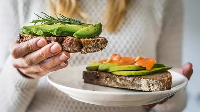 millennial woman eating avocado toast saving her money