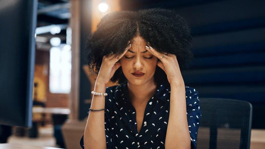 Shot of a tired young female designer looking stressed with her hands in her hair while contemplating in the office at work.