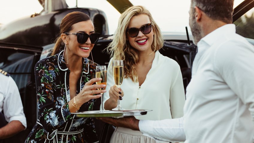 two successful women enjoying champagne after a helicopter ride