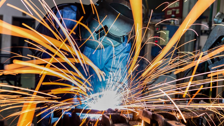 Worker is welding in car factory.