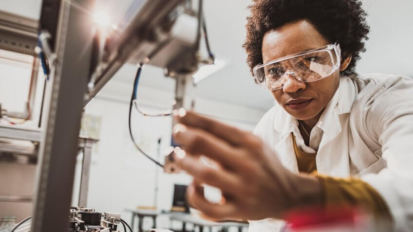Low angle view of lab worker examining machine part while working in a lab.