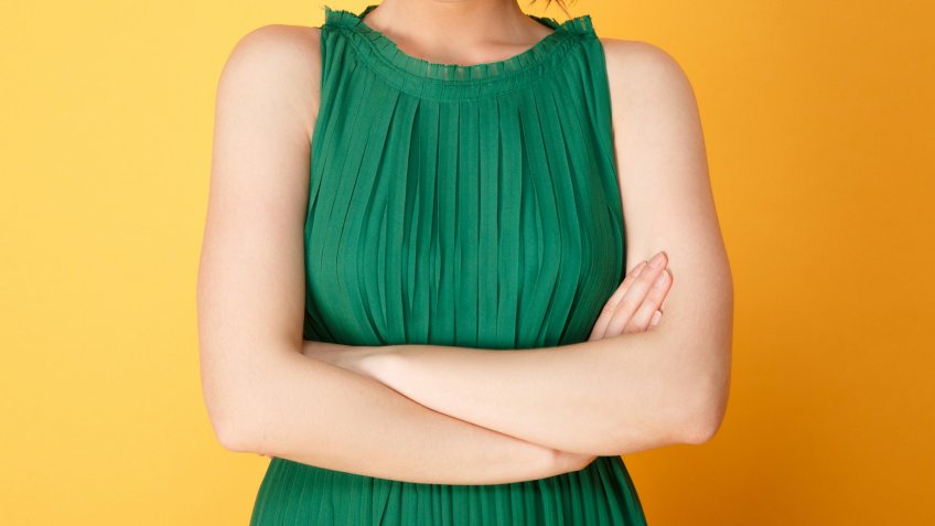 Portrait of offended woman with arms crossed looking at camera isolated on orange.