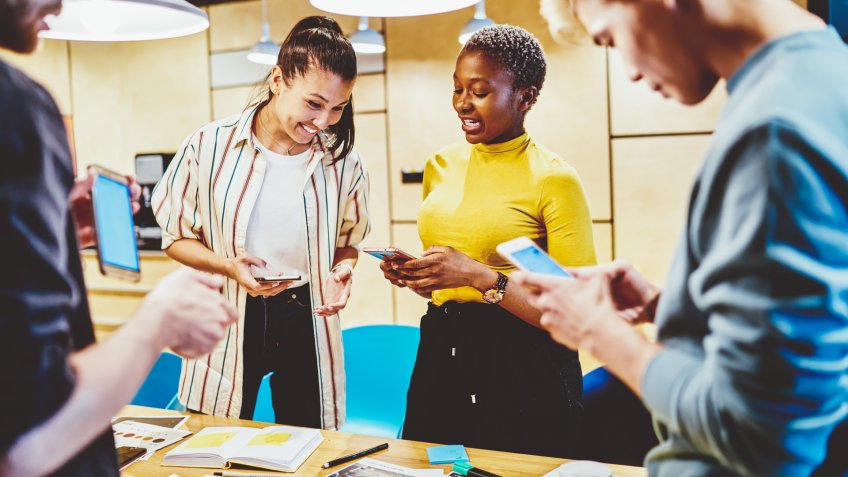 young colleagues cheerfully talking while on smartphones