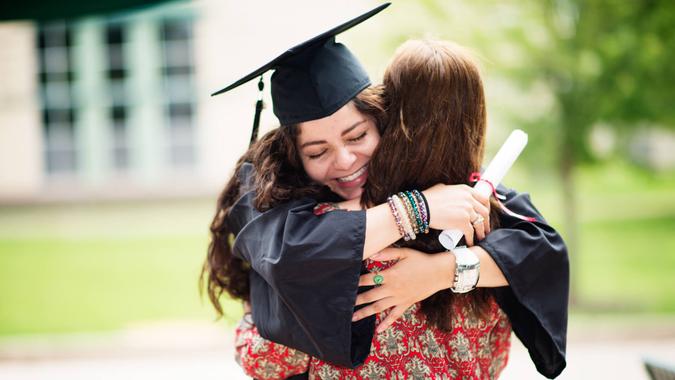 Female college student hugging her mother on graduation date.
