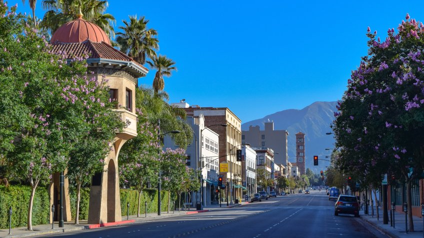 An empty street in downtown Pasadena, California with palm trees and retail stores.
