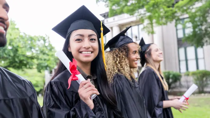 Happy Hispanic female graduate holds her diploma.