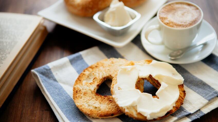 Montreal style bagels on a plate with cream cheese and coffee.