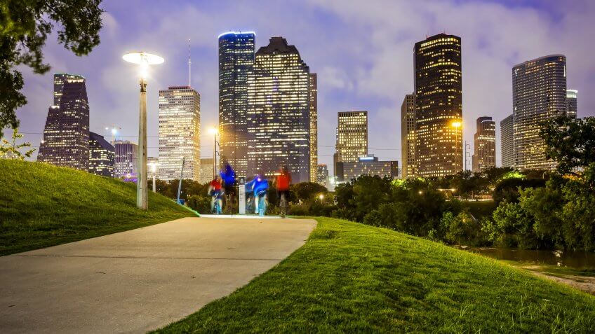 Houston city skyline as night falls and people enjoying Eleanor Tinsley Park.