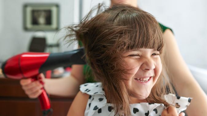 enjoy day at hairsalon sweet little girl at harsalon drying hair and laughing.