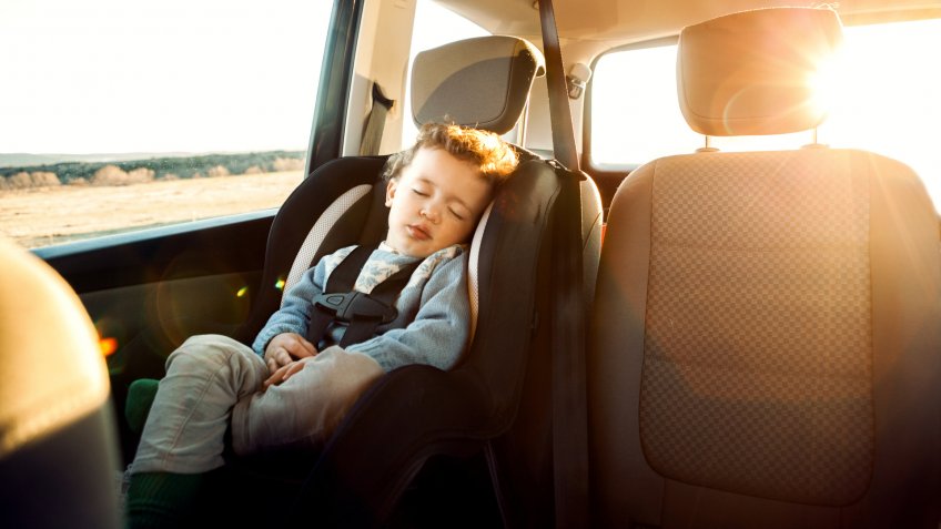 Smiling little boy sitting car in child seat.