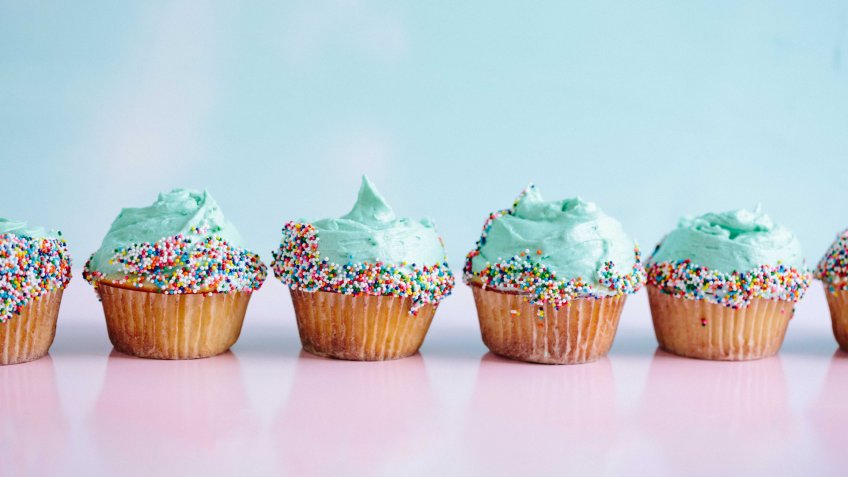 mini cupcakes with light teal frosting and sprinkles in a row
