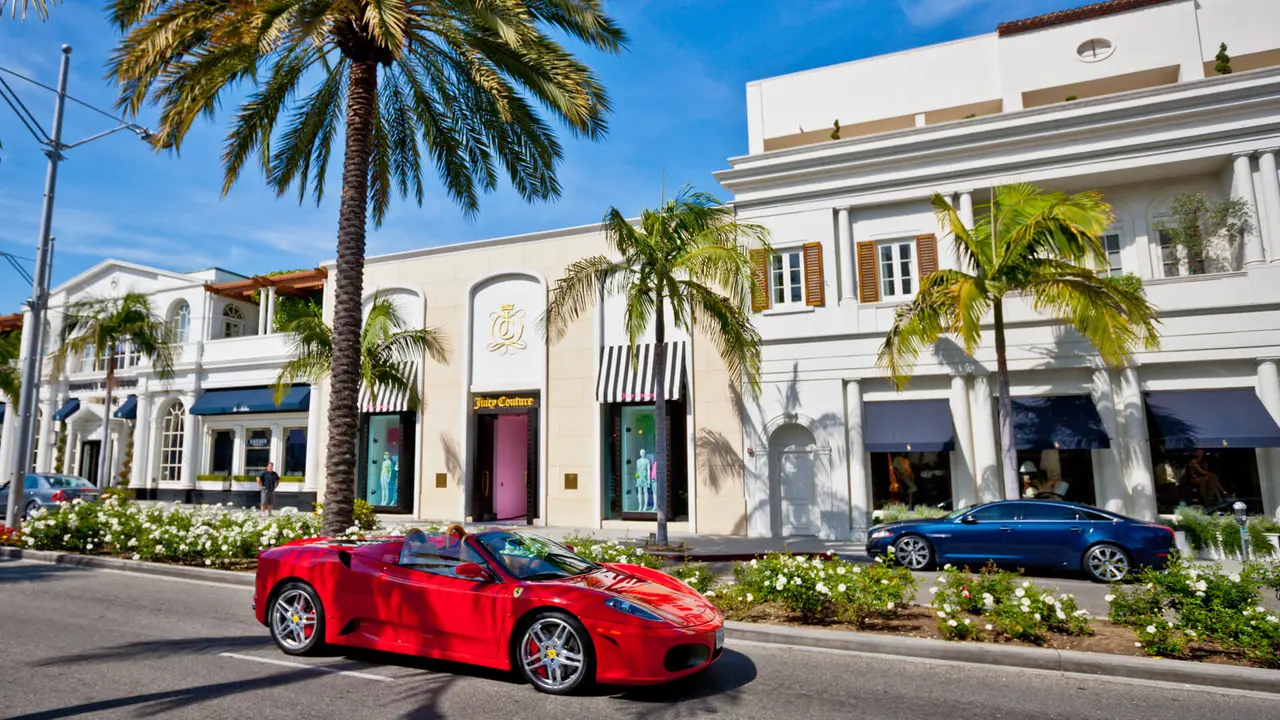 Beverly Hills, USA - May 3, 2013: Rodeo Drive, Beverly Hills, Juicy Couture store on the other side of Rodeo Drive, red Ferrari moving on the street.