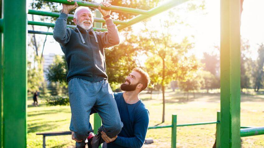 Happy good looking father and son exercising together in park.