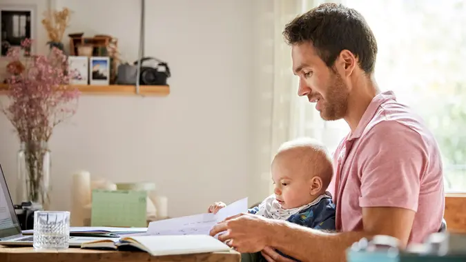 Mid adult father analyzing documents while sitting with baby boy.