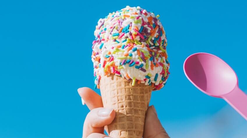 ice cream cone with sprinkles and a pink spoon