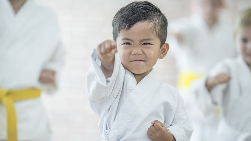 A multi-ethnic group of elementary age children are taking a karate class together at a health club.