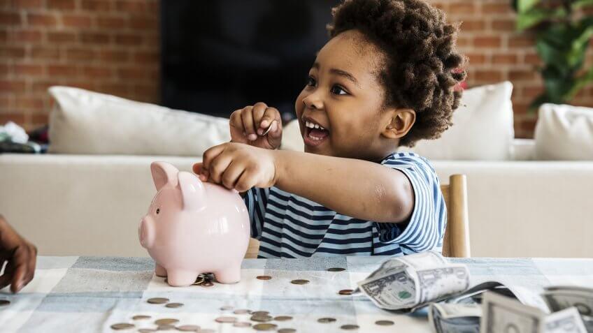 Black boy collecting money to piggy bank.