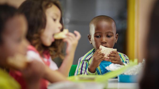 Pre-school children on their lunch break eating sandwiches.