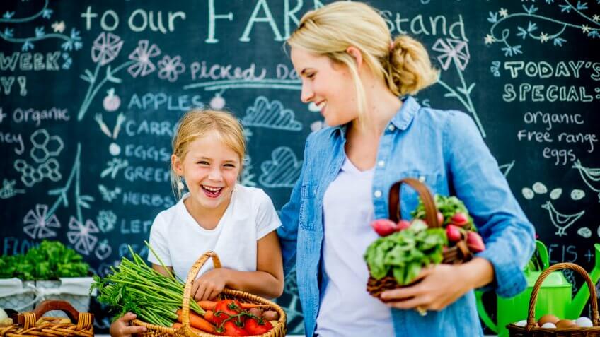 A mother and daughter are at a farmer's market together.
