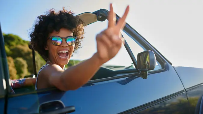 Shoot of young woman leaning out the window of car.