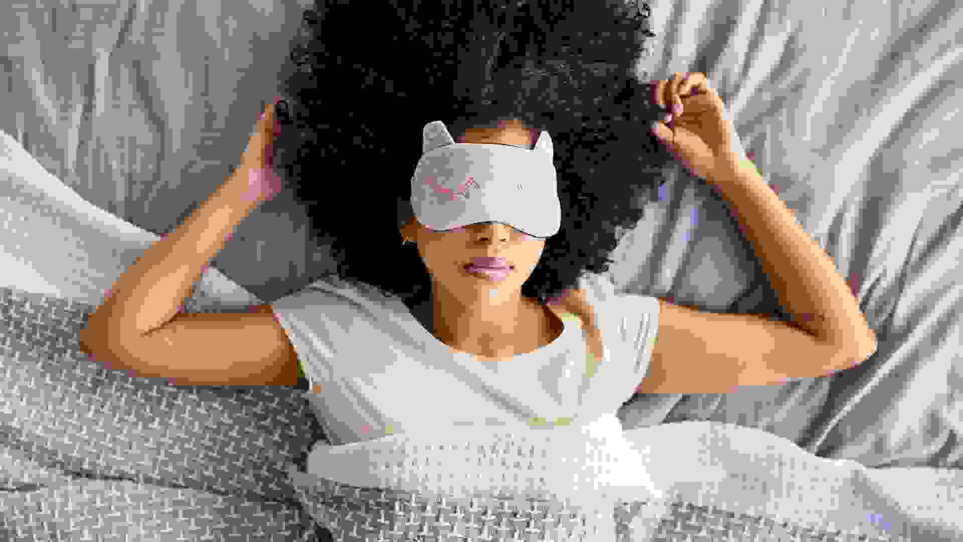 Shot of a young woman sleeping with a mask on in bed.