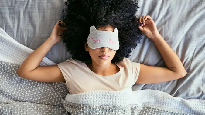 Shot of a young woman sleeping with a mask on in bed.