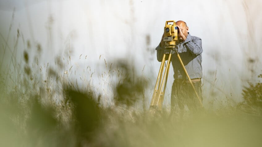 Surveyor Using Theodolite to Measure Land.