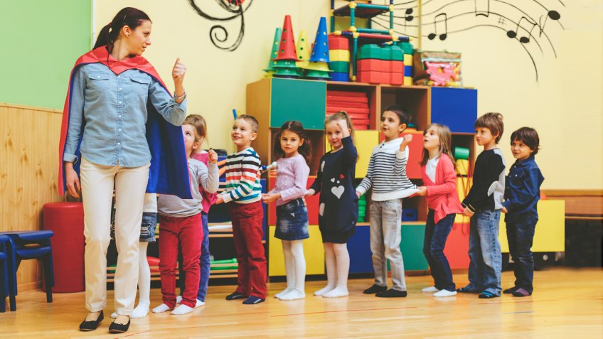 Group of children playing with their teacher in kindergarten.